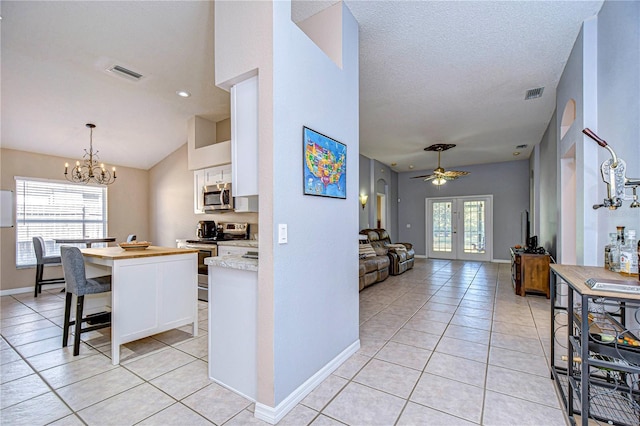 kitchen with light tile patterned floors, stainless steel appliances, a kitchen breakfast bar, white cabinets, and french doors