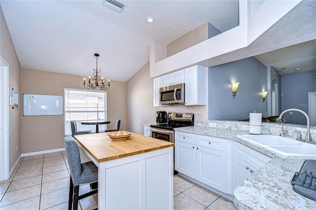 kitchen with stainless steel appliances, white cabinetry, a center island, and sink