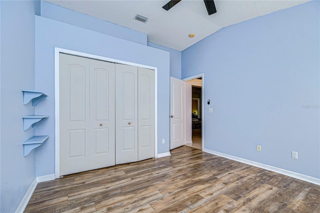 unfurnished bedroom featuring hardwood / wood-style flooring, lofted ceiling, ceiling fan, and a closet