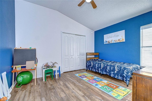 bedroom with lofted ceiling, wood-type flooring, a textured ceiling, a closet, and ceiling fan