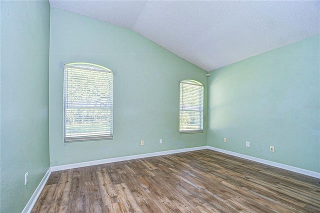 spare room with lofted ceiling, dark hardwood / wood-style flooring, and a textured ceiling