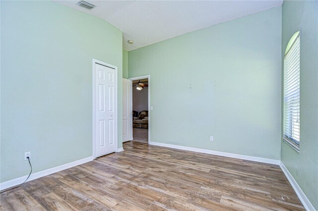 unfurnished room featuring hardwood / wood-style flooring and vaulted ceiling