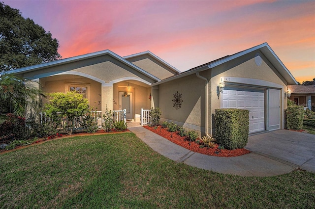 ranch-style home with a porch, a garage, concrete driveway, stucco siding, and a front yard