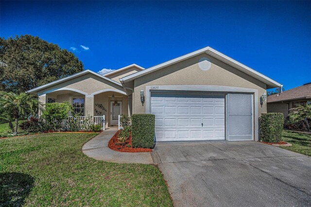 ranch-style home with a garage, driveway, a front lawn, and stucco siding