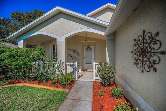 doorway to property featuring a porch and stucco siding