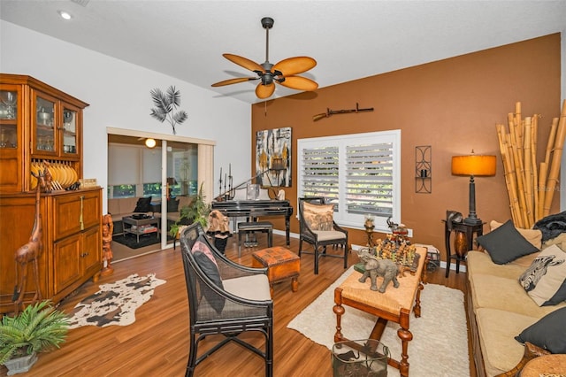 living room with ceiling fan, baseboards, and wood finished floors