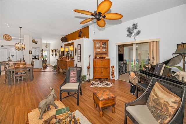 living room featuring ceiling fan with notable chandelier and wood finished floors