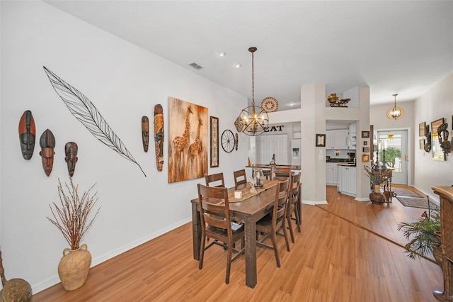 dining area featuring light wood finished floors, baseboards, visible vents, and a chandelier