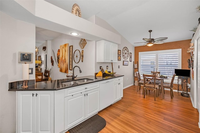 kitchen featuring light wood finished floors, dark countertops, vaulted ceiling, a sink, and dishwasher