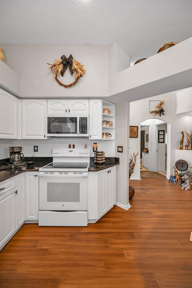 kitchen with dark countertops, white electric range, stainless steel microwave, and white cabinets