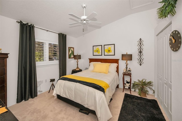 bedroom with lofted ceiling, ceiling fan, a textured ceiling, light carpet, and attic access