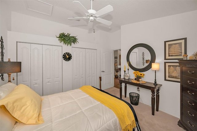 bedroom featuring light carpet, a ceiling fan, and two closets