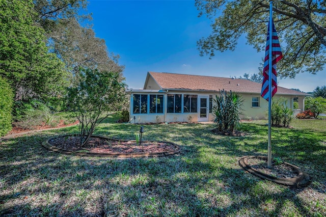 back of house with a sunroom, a lawn, and stucco siding