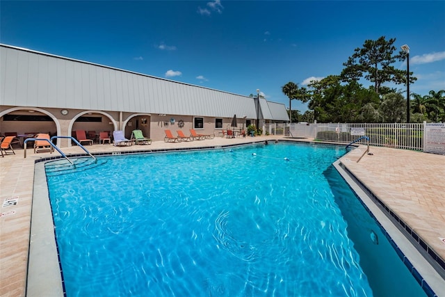 community pool with a patio area and fence