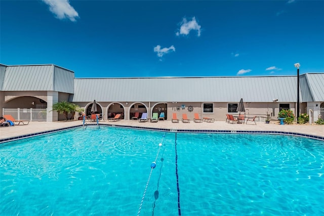 community pool with a patio area and fence