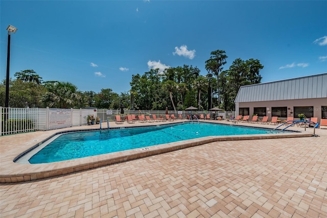 community pool with a patio area and fence