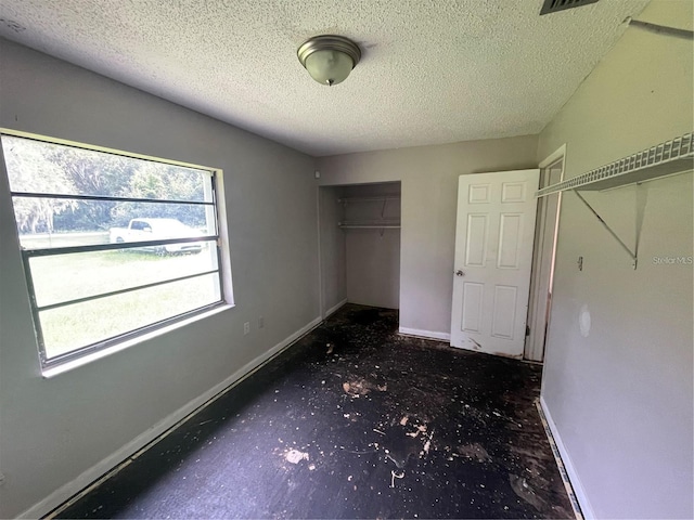 unfurnished bedroom with dark colored carpet, a textured ceiling, and a closet