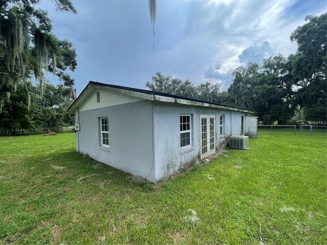 view of property exterior with cooling unit and a lawn