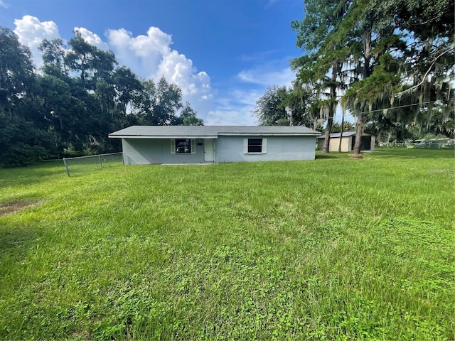 rear view of property featuring a yard and a storage unit