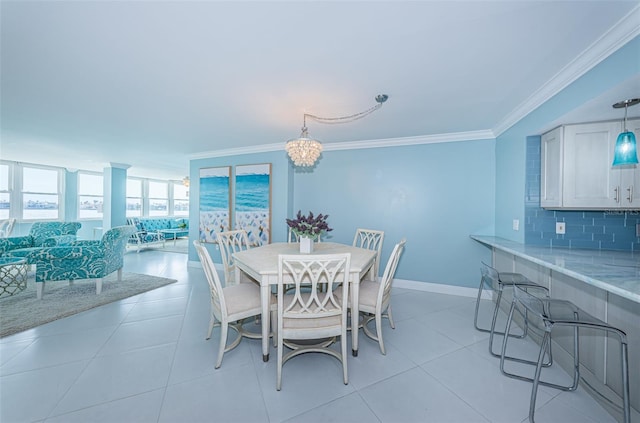 dining space featuring light tile patterned floors, ornamental molding, a notable chandelier, and baseboards