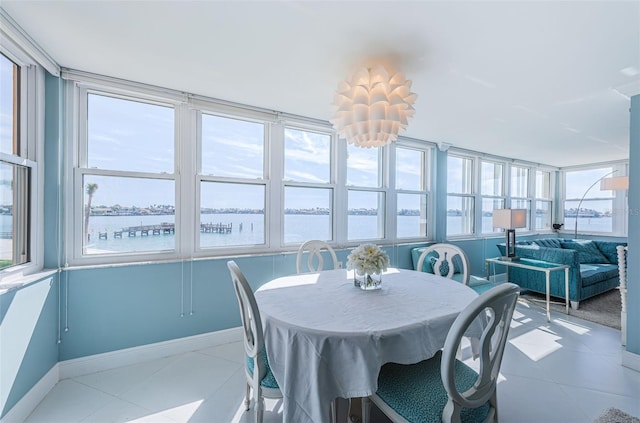 dining room featuring a water view, baseboards, and light tile patterned floors