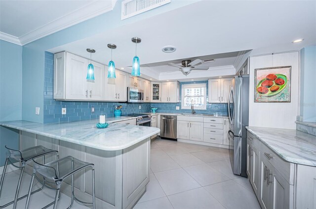 kitchen with pendant lighting, crown molding, appliances with stainless steel finishes, glass insert cabinets, and a peninsula