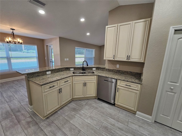 kitchen with sink, dark stone countertops, stainless steel dishwasher, kitchen peninsula, and cream cabinetry