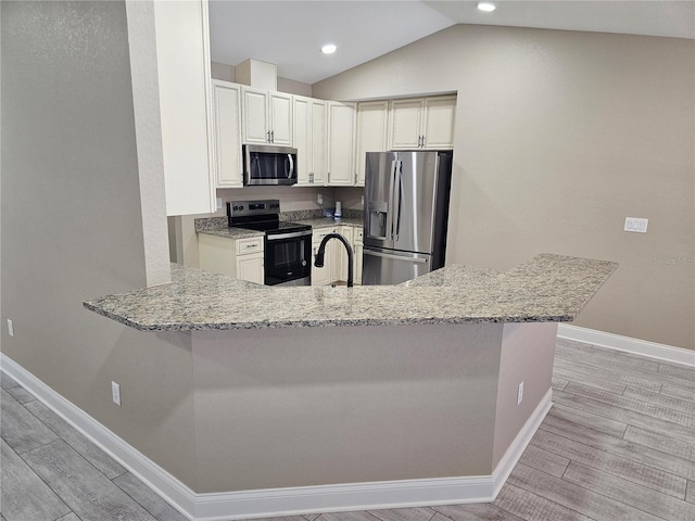 kitchen with appliances with stainless steel finishes, kitchen peninsula, light stone countertops, and light wood-type flooring