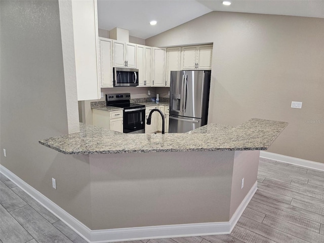 kitchen with light stone countertops, vaulted ceiling, stainless steel appliances, and kitchen peninsula