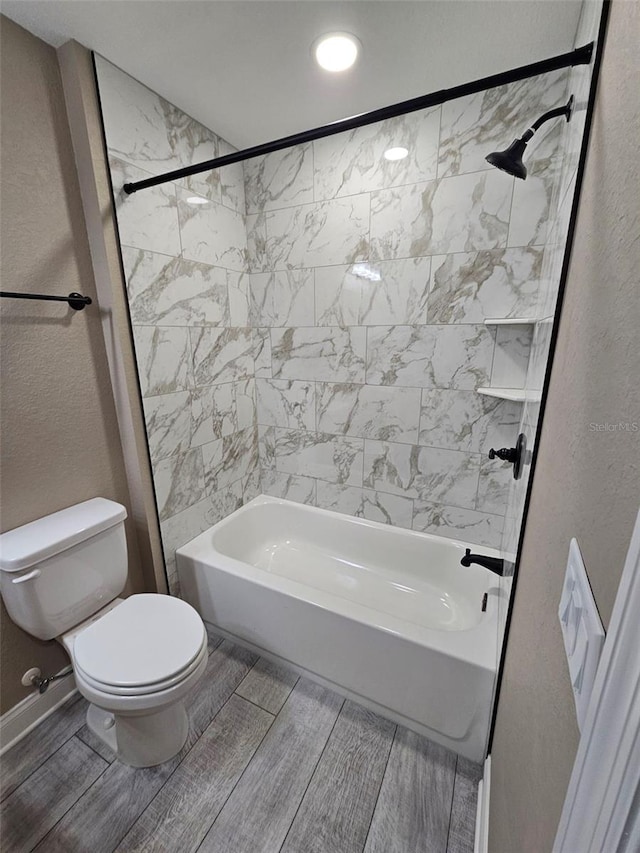 bathroom featuring tiled shower / bath combo and toilet