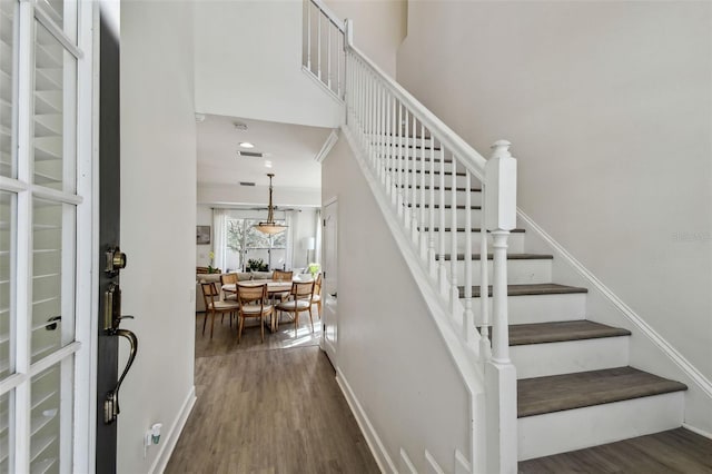 stairway with hardwood / wood-style flooring and a towering ceiling