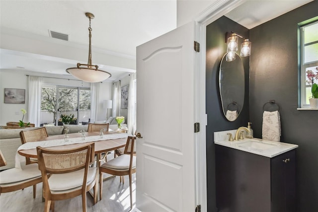 dining space with hardwood / wood-style flooring, crown molding, sink, and a wealth of natural light