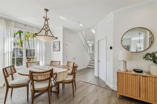 dining area featuring hardwood / wood-style flooring, crown molding, and plenty of natural light