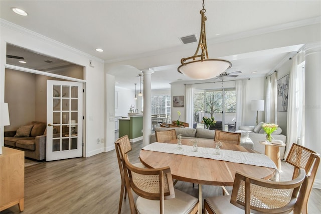 dining room featuring crown molding, decorative columns, and hardwood / wood-style floors