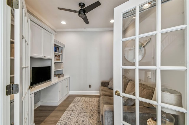 unfurnished office featuring french doors, built in desk, ornamental molding, dark hardwood / wood-style flooring, and ceiling fan