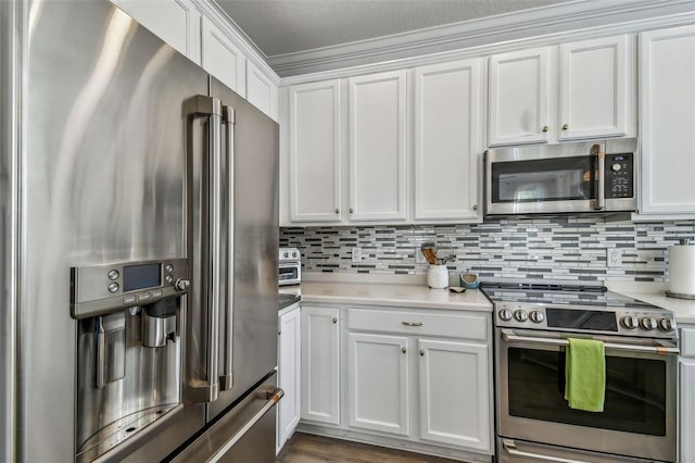 kitchen featuring tasteful backsplash, ornamental molding, stainless steel appliances, and white cabinets