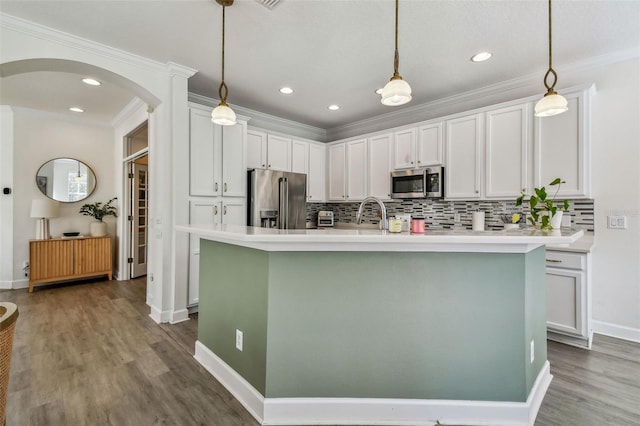 kitchen with crown molding, white cabinetry, hanging light fixtures, stainless steel appliances, and a center island with sink