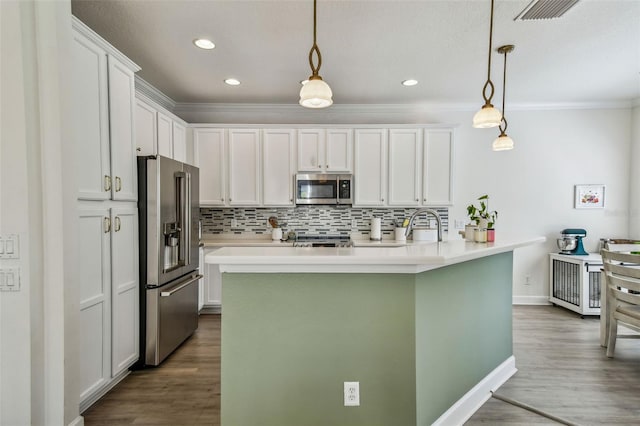 kitchen with tasteful backsplash, a center island with sink, pendant lighting, stainless steel appliances, and white cabinets