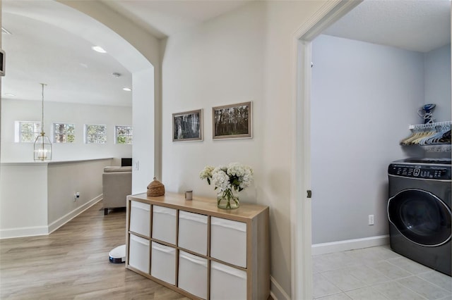 clothes washing area with washer / dryer and light hardwood / wood-style flooring