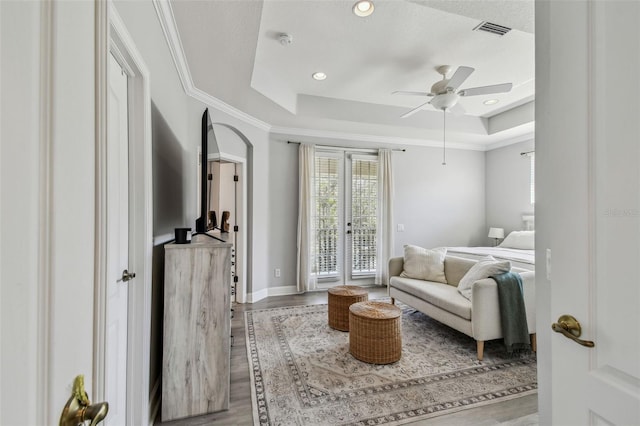 interior space with a raised ceiling, ceiling fan, crown molding, and light wood-type flooring