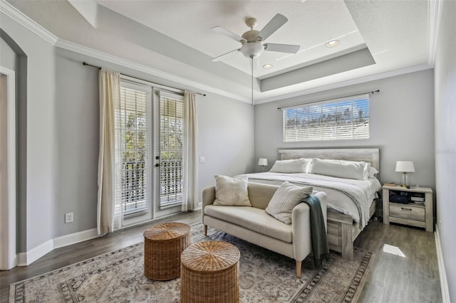 bedroom with dark hardwood / wood-style floors, ornamental molding, access to exterior, a raised ceiling, and french doors