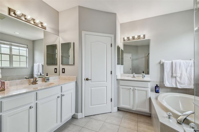 bathroom with a relaxing tiled tub, tile patterned floors, and vanity