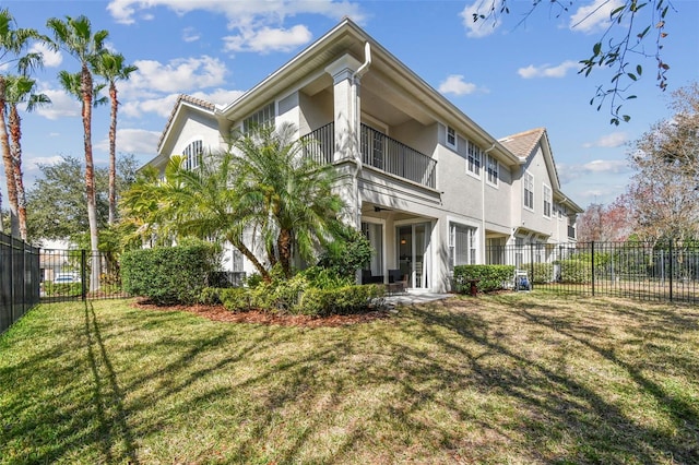 rear view of property with a balcony and a lawn