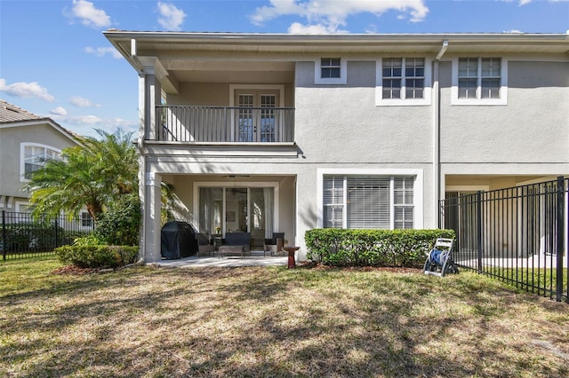 rear view of house with a balcony, a yard, and a patio area