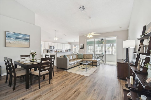 living room featuring lofted ceiling, light hardwood / wood-style flooring, and a textured ceiling