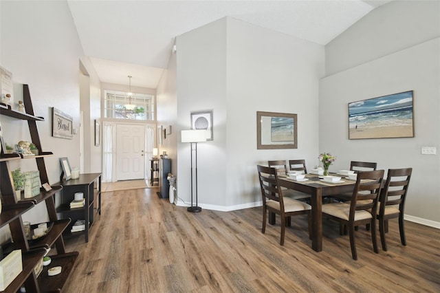 dining space with vaulted ceiling, hardwood / wood-style floors, and a notable chandelier