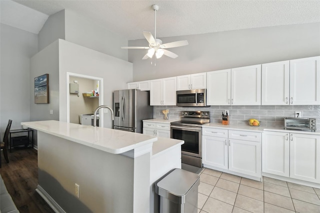 kitchen with stainless steel appliances, white cabinetry, tasteful backsplash, and light tile patterned floors