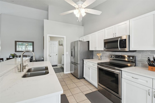 kitchen with light tile patterned flooring, appliances with stainless steel finishes, white cabinetry, sink, and backsplash