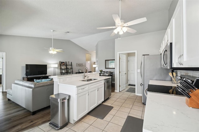 kitchen featuring light tile patterned flooring, lofted ceiling, sink, white cabinetry, and appliances with stainless steel finishes