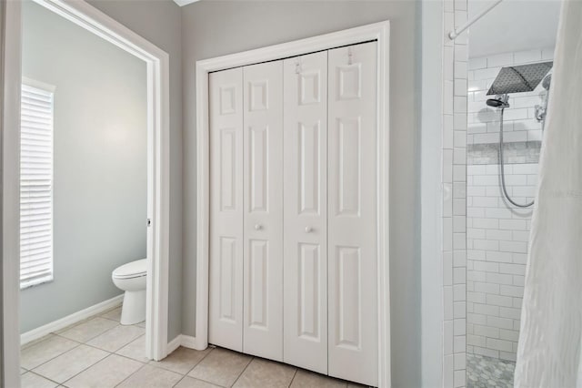 bathroom with a tile shower, tile patterned flooring, and toilet